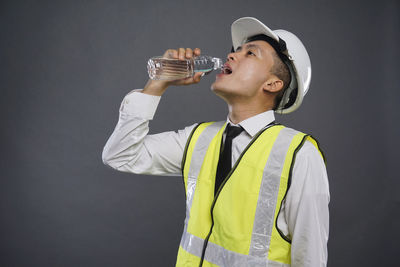 Young man drinking glass against white background