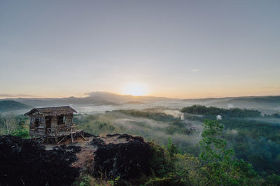 Scenic view of landscape and houses against sky during sunset