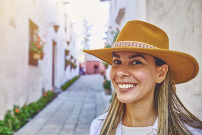 Portrait of young woman wearing hat standing on footpath