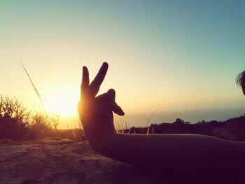 Close-up of silhouette hand against sunset sky