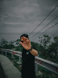 Woman standing by railing against sky