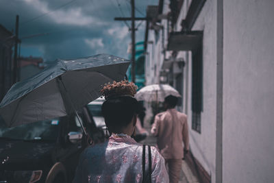 Rear view of people walking on wet street in rainy season