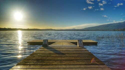 Pier over lake against sky during sunset