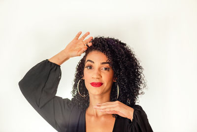 Cheerful and quiet young woman with hands on chin and hair looking at camera. 