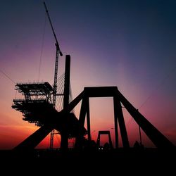 Low angle view of silhouette cranes against sky during sunset