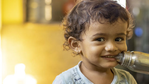 Laughing baby chewed with the teeth of nibble a milk bottle