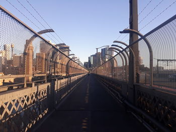 Footbridge in city against clear sky