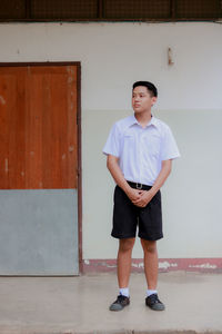 Portrait of boy standing against wall