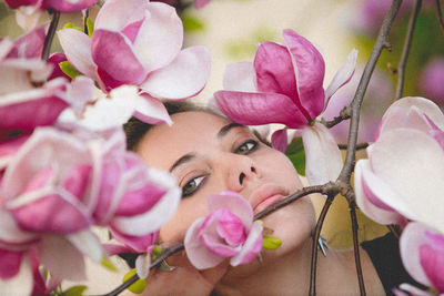 Portrait of beautiful woman seen through pink magnolia flowers