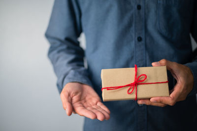 Midsection of man holding paper against white background