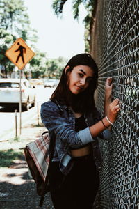 Portrait of young woman standing against wall