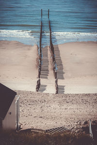 High angle view of wooden posts at sandy beach