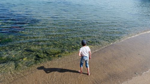 Rear view full length of boy on shore at beach