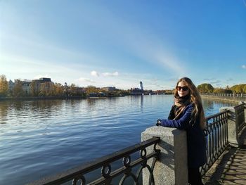 Portrait of woman standing by railing against sky