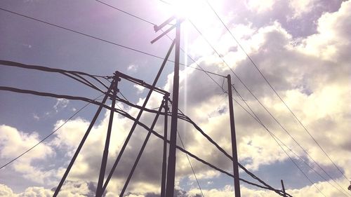 Low angle view of electricity pylon against cloudy sky