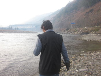 Rear view of man on lake against sky