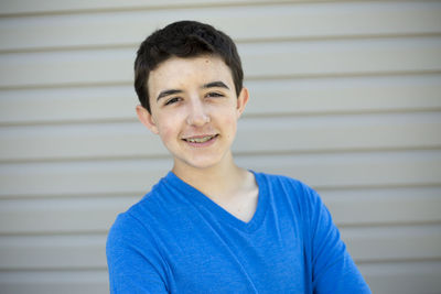 Portrait of teenage boy with braces standing by wall