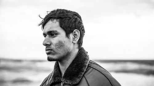 Portrait of young man looking away against sky