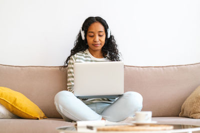 Young woman using laptop while sitting on sofa at home