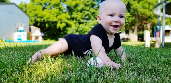Close-up of cute baby boy lying on grassy field