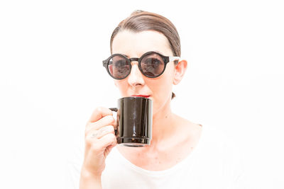 Close-up of woman holding camera against white background