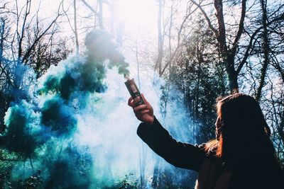Woman with green smoke in forest