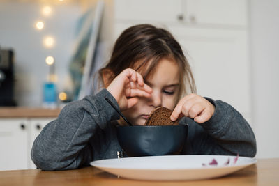 Close-up of cute girl eating food at home