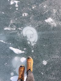 Feet of a person standing on the ice of a frozen lake