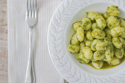 A plate with gnocchi with basil pesto and a fork.