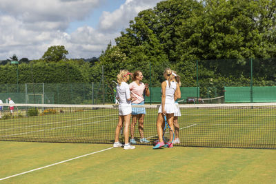 Mature women finishing tennis match on grass court