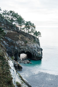 Rock formation by sea against sky