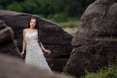 Portrait of young woman on rock against trees