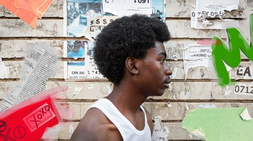 Side view of young man looking away against wall