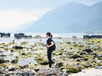 Rear view of woman standing on beach against sky