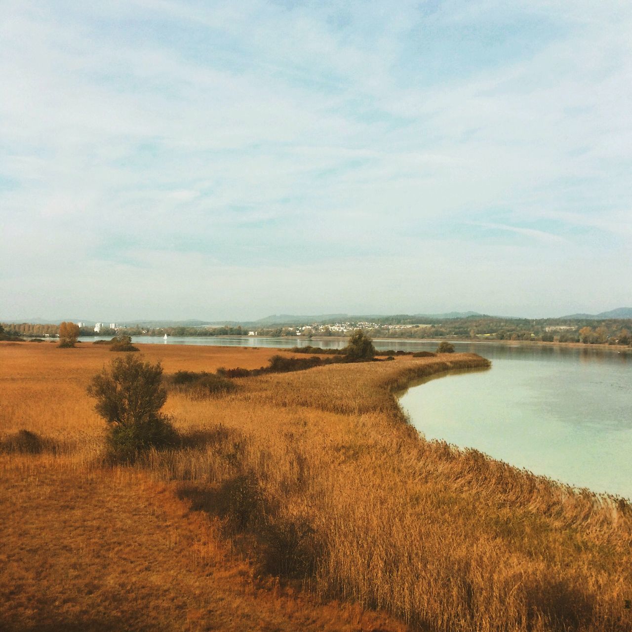 sky, tranquil scene, tranquility, water, scenics, landscape, beauty in nature, cloud - sky, grass, nature, field, cloud, horizon over land, idyllic, lake, rural scene, day, cloudy, non-urban scene, outdoors