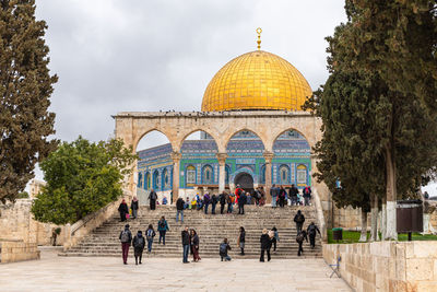 Group of people in front of historic building against sky