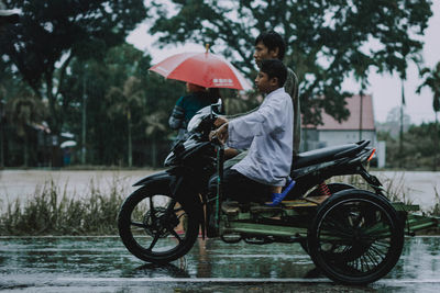 Woman with umbrella sitting in rain