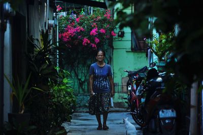 Full length portrait of woman standing against plants
