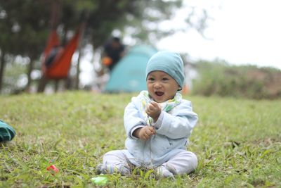 Portrait of cute boy sitting on grass in field