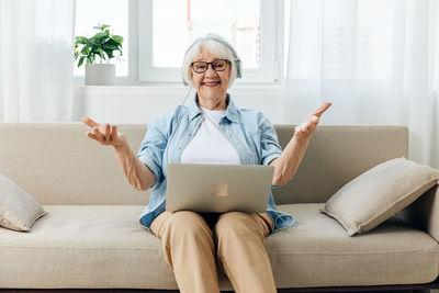 Young woman using laptop while sitting on sofa at home