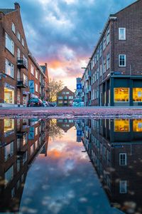 Reflection of buildings in puddle against sky