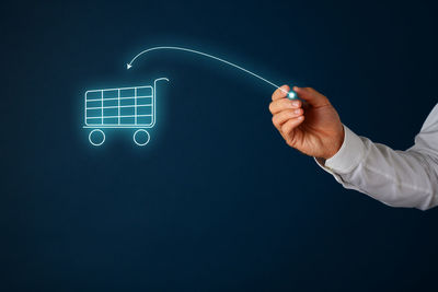 Midsection of man holding illuminated lighting equipment against black background