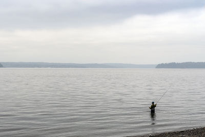 Man fishing in sea against sky