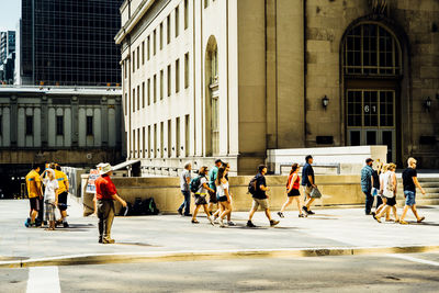 People walking against buildings on sunny day