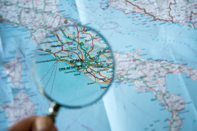 Cropped hand holding magnifying glass over map