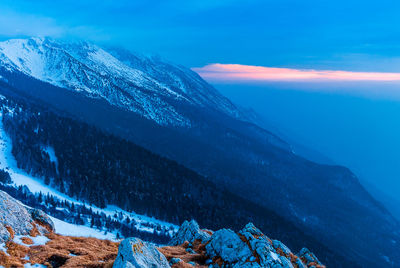 Scenic view of sea and mountains against blue sky