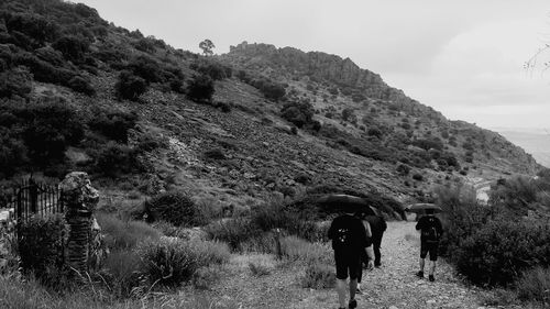 Rear view of people walking on mountain against sky