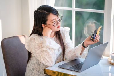 Young woman using phone while sitting on table