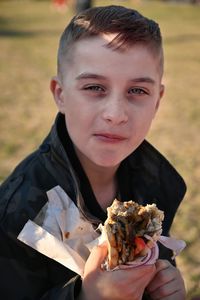 Portrait of young boy holding ans eating street food