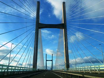 Low angle view of suspension bridge against cloudy sky